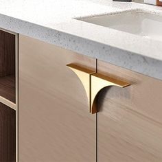 a kitchen counter with a sink and gold faucet on it's side