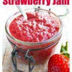 a strawberry jam in a glass jar with a spoon