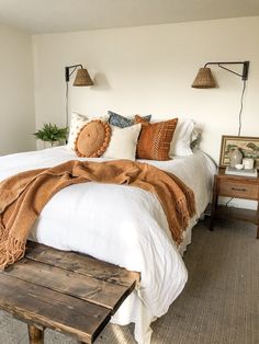 a bed with white sheets and blankets on top of it next to a wooden table