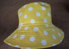 a yellow and white polka dot sun hat on the ground with a person's foot next to it