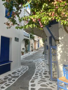 an alley way with blue and white buildings on both sides, surrounded by greenery