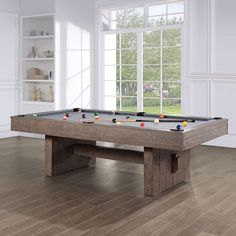 a pool table in the middle of a room with windows and wood flooring on both sides