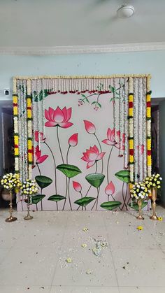 a decorated room with flowers and candles on the floor in front of a large wall