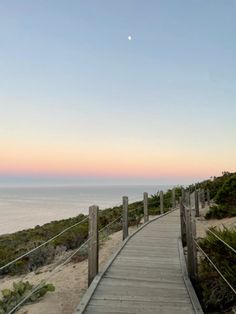 a wooden walkway leading to the beach at sunset