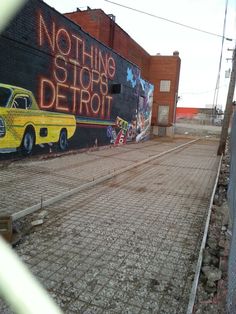 a yellow truck parked in front of a building with graffiti on it's side