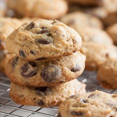 chocolate chip cookies stacked on top of each other on a cooling rack with more cookies in the background