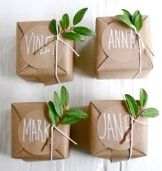 three wrapped gift boxes with green leaves tied to them, labeled with name and date