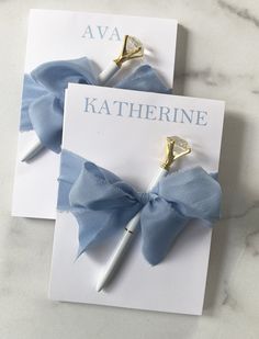 two blue and white bowknots on top of a note with a pen