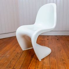 a white chair sitting on top of a hard wood floor next to a wooden wall