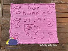 a pink crocheted blanket with the words happy birthday written on it