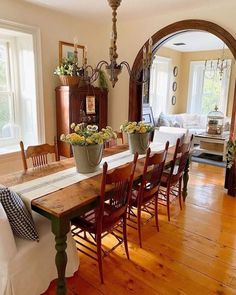 a dining room table with chairs and vases on top of it in front of a mirror