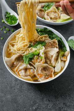 someone is holding chopsticks over a bowl of noodles with meat and veggies