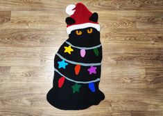 a black cat wearing a santa hat and lights on it's back legs is sitting on the floor