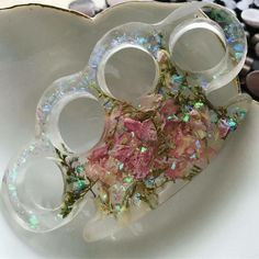 a white bowl filled with pink flowers and glass goblets on top of rocks