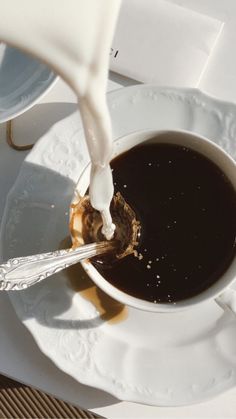 a cup of coffee is being poured into the saucer with a spoon on it