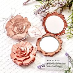 three rose shaped compact mirrors sitting next to each other on a table with lavenders