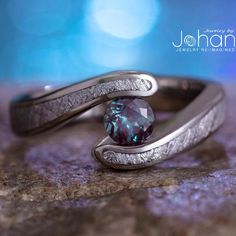 two wedding rings with a blue diamond in the middle and silver bands around them on top of a rock