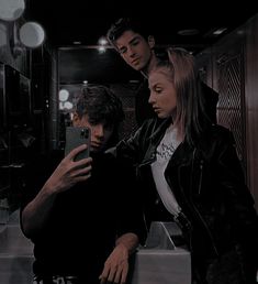 three people standing in front of a mirror looking at their cell phones and taking a selfie