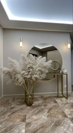 a vase with some white flowers on top of a table in front of a mirror