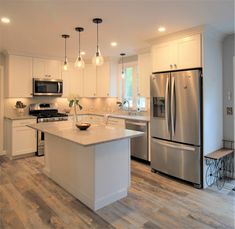 a large kitchen with an island and stainless steel refrigerator freezer combo in the center