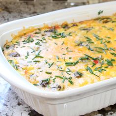 a casserole dish with cheese and vegetables in it sitting on a marble counter