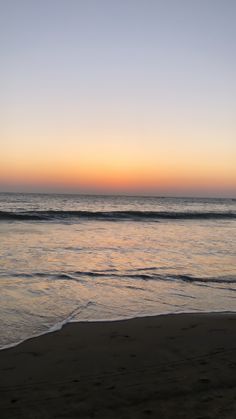 the sun is setting over the water at the beach