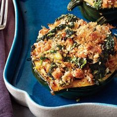 two stuffed peppers on a blue plate with silverware