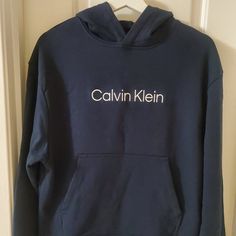 With A Relaxed Fit And Iconic Logo Styling, This Calvin Klein Sweatshirt Features A Plush Cotton Knit Blend For Premium Comfort. Finished With A Drawstring Hood, A Kangaroo Pocket And Ribbed Knit Trim For A Snug Fit. Classic Logo At Front For An Iconic Design Plush Cotton French Terry For Super Soft, Loungewear Comfort Drawstring Hood + Long Sleeves Kangaroo Pocket + Ribbed Knit Trim For A Snug Fit Machine Wash 88% Cotton 12% Polyester Blue Fleece Tops With Logo Print, Blue Fleece Tops With Embroidered Logo, Navy Hoodie With Embroidered Logo For Fall, Navy Casual Hoodie With Embroidered Logo, Blue Logo Print Sweatshirt For Loungewear, Navy Hoodie With Embroidered Logo, Navy Long Sleeve Hoodie With Embroidered Logo, Calvin Klein Sweatshirt, Fit Logo