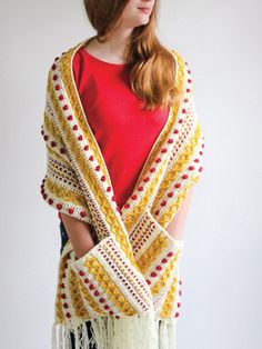 a woman wearing a yellow and white crocheted shawl with fringes on it