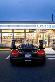 a black sports car is parked in front of a laweon auto shop at night