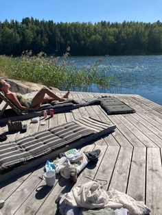 a woman laying on a deck next to a body of water