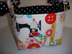 a sewing basket is decorated with black and white polka dots, colorful buttons, and a sewing machine