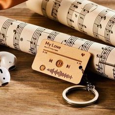 a wooden keychain with music notes on it next to two rolls of wrapping paper