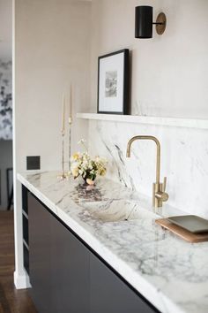 a marble counter top in a kitchen with gold faucets and flowers on it