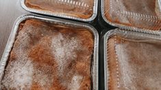 four pans filled with brownies covered in powdered sugar on top of a table