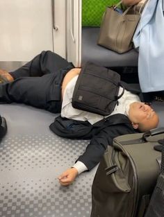 a man laying on the floor with his luggage in front of him and two other suitcases behind him