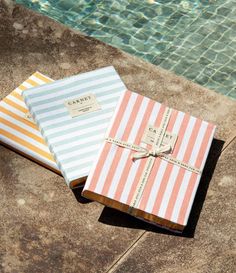 two wrapped gift boxes sitting next to a swimming pool