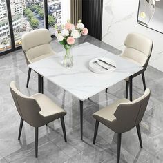 a white marble dining table surrounded by beige chairs and a vase with flowers on it