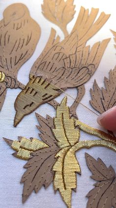 someone is cutting out gold leaf designs on fabric