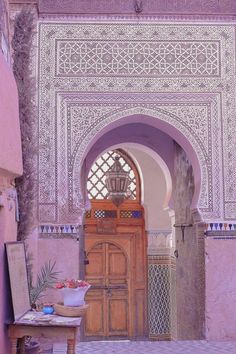 an archway leading into a room with pink walls and tile on the floor, along with a wooden cabinet