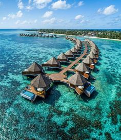 an aerial view of the over water resort in the middle of the ocean with thatched huts