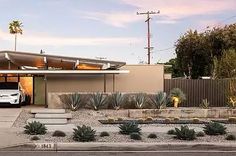 a white car is parked in front of a house with cactus and cacti