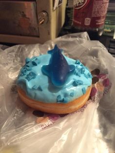 a blue frosted doughnut with a shark fin on top sitting on plastic wrap