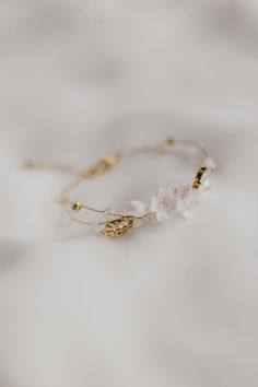 a white flower and gold bracelet on top of a white cloth covered tablecloth,