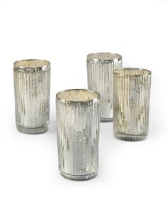 four silver colored glass candlesticks sitting next to each other