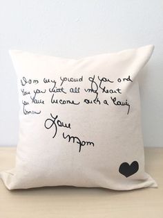 a pillow with writing on it sitting on top of a wooden table next to a white wall