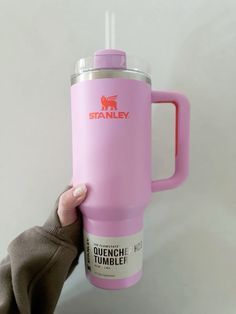 a person holding up a pink travel mug