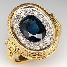 This stunning ring is decorated with engraved scroll and rope motifs and is centered with one (1), bezel set, oval mixed cut natural sapphire. The sapphire is bordered with sixteen (16), bead set, round single cut diamonds. The ring measures 16.8mm at the top, rises 4.3mm above the finger, tapering to 3.5mm wide and 1.8mm thick at the base of the shank. This ring is currently a size 3.5. Luxury Oval Sapphire Ring With Bezel Setting, Antique Oval Sapphire Ring For Formal Occasions, Exquisite Oval Sapphire Ring With Diamond Accents, Heirloom Oval Sapphire Ring With Intricate Design, Oval Sapphire Ring With Intricate Design, Luxury Sapphire Ring With Intricate Design, Antique Oval Sapphire Ring With Diamond Accents, Luxury Sapphire Ring With Intricate Design For Formal Occasions, Diamond Halo Ring