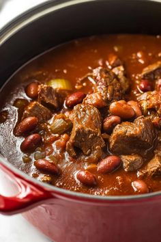 a red pot filled with meat and beans