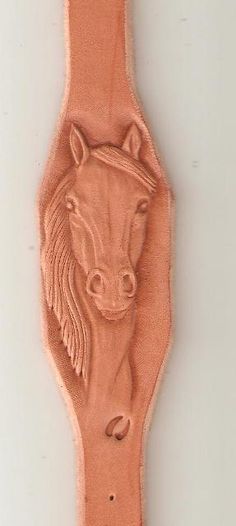 a horse head is carved into the side of a leather watch band, which has been stitched together